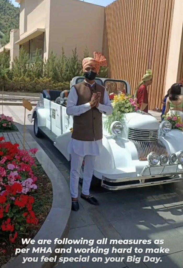 Vintage car for wedding following covid related guidelines, driver is wearing a mask at wedding venue.