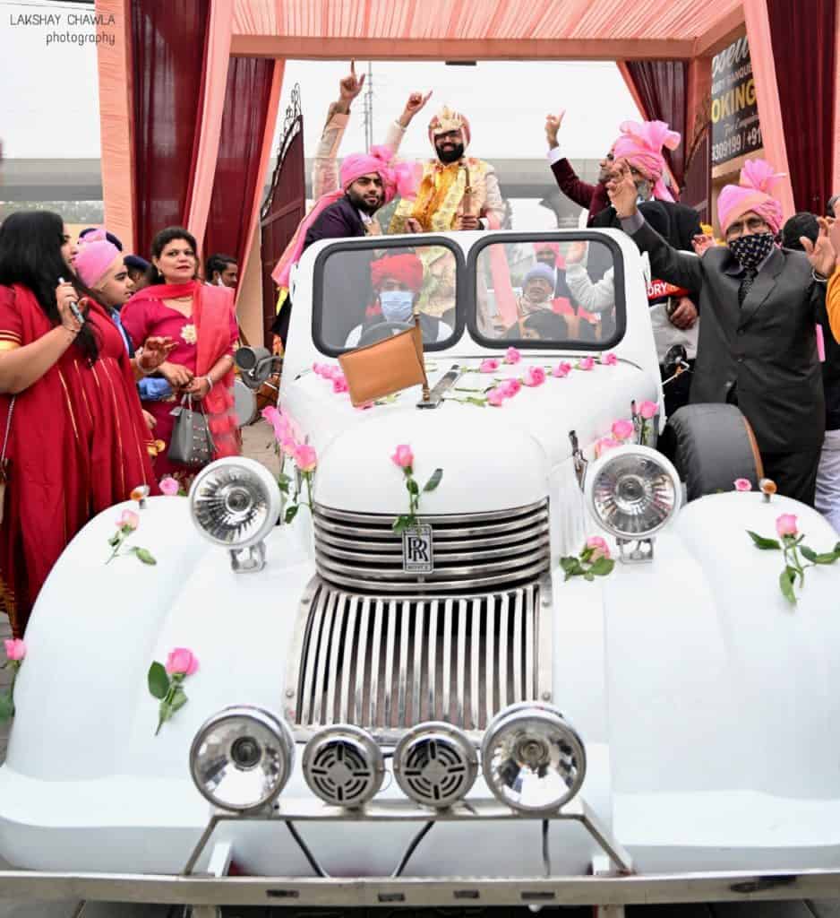An indian guy going for his baaraat on white vintage car